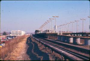 Train Station: LIRR Hicksville Station north and south platforms (left to right) on embankment west of the viaduct; track-side view east (1970) [This image is used with permission of Hicksville Public Library]